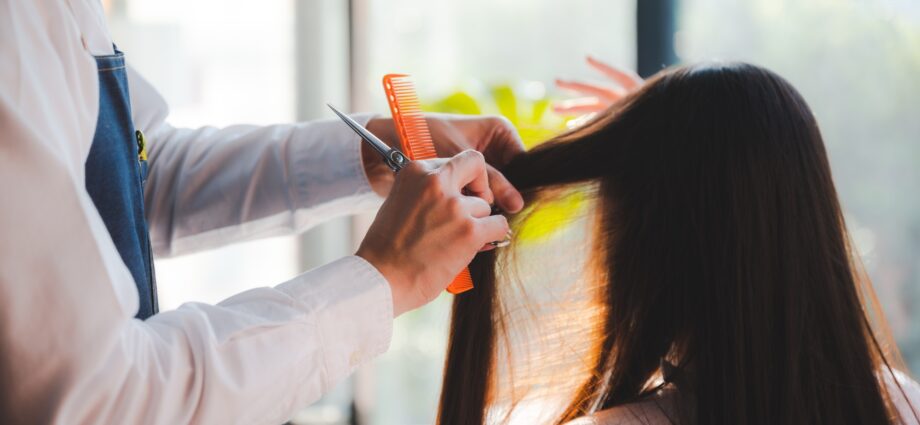 stylist cutting woman's hair in salon, Hairdresser coiffure trimming brown hair with scissors